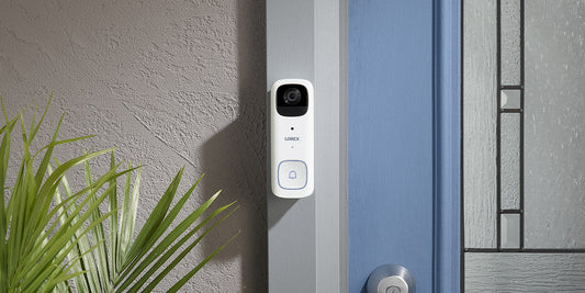 Lorex 2K battery-powered video doorbell mounted next to a front door, shown in a modern residential entryway setting.