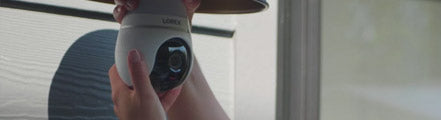 Hands installing a Lorex 2K Wi-Fi lightbulb security camera into an outdoor light fixture, demonstrating easy setup for smart home surveillance.