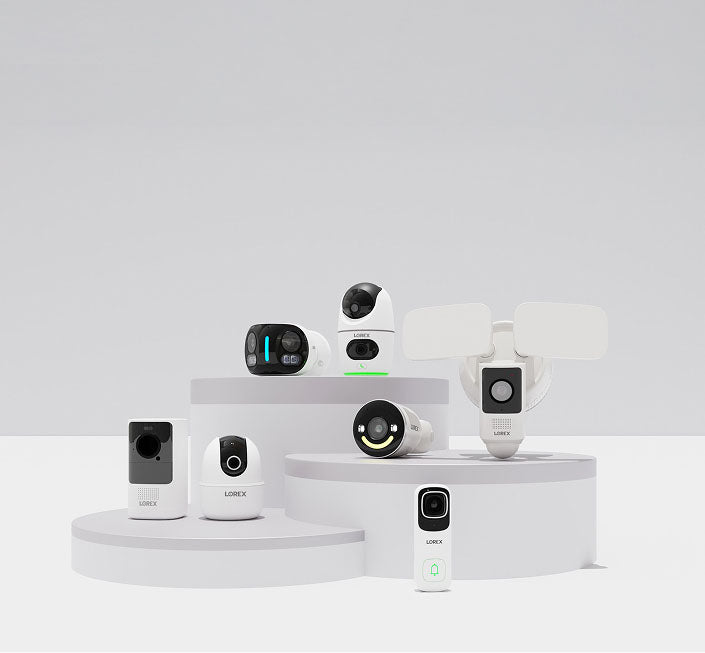 Collection of smart security cameras from Lorex, including indoor and outdoor wireless (Wi-Fi) Cameras, floodlight, and video doorbell camera models displayed on white podiums.
