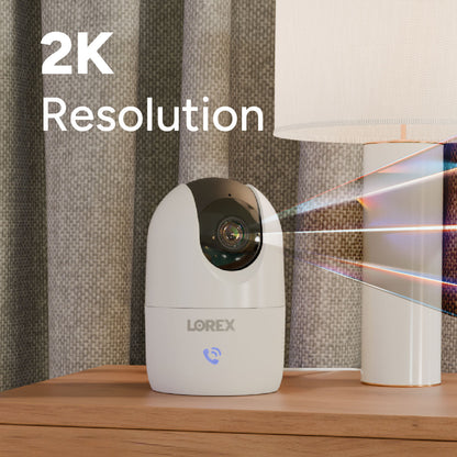 Lorex Connect 2K indoor Wi-Fi pan-tilt camera on a wood surface with a patterned backdrop.
