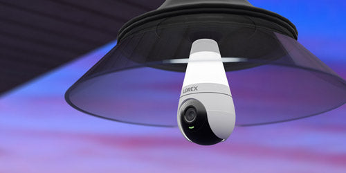Lorex 2K Wi-Fi lightbulb security camera mounted in a modern black outdoor fixture, combining smart lighting and surveillance for enhanced home security at dusk.