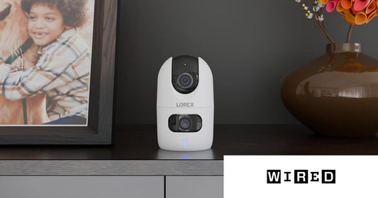Lorex Connect 2K Dual-Lens Indoor Camera beside a framed photo of a child and dog, featured in WIRED's